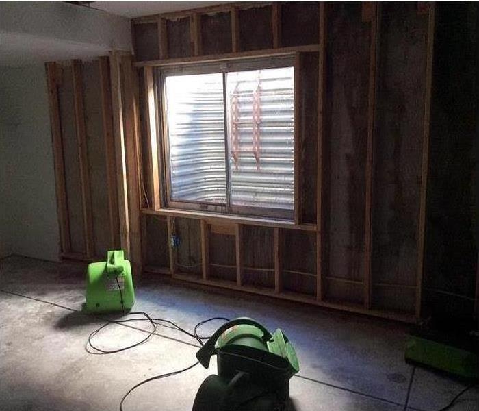 a room with drywall removed and drying equipment set up on the floor
